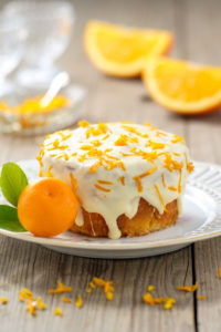 Small orange cake with white icing on plate Small orange cake with white icing on plate
